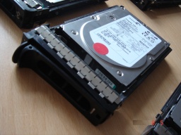 A Hard Drive taken from a Dell Server shown in it's caddy. The drives are 3.5inch and 146gb each. The drives are lockable and have a red dot on the case. To the edge of the photo you can see the other drives from the array.
